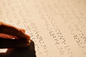 A hand reading embossed braille on paper, illustrating the ADA website accessibility lawsuit against Alastin Skincare
